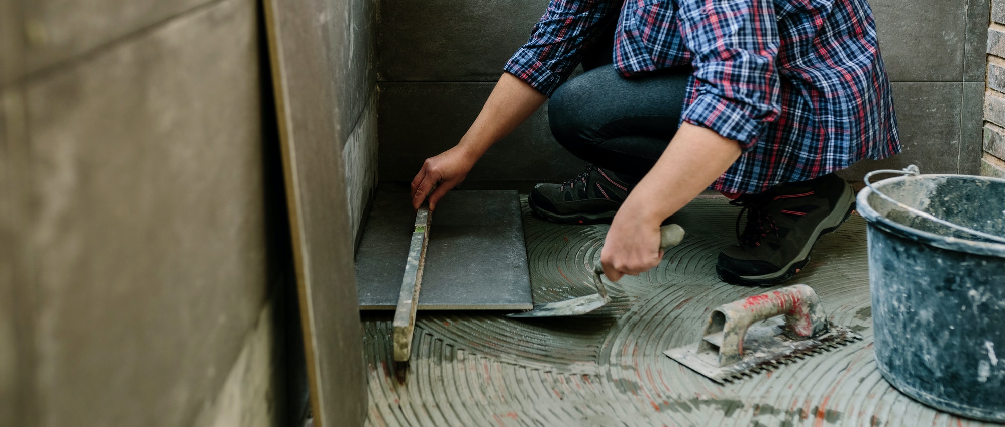 Female bricklayer checking floor with a level