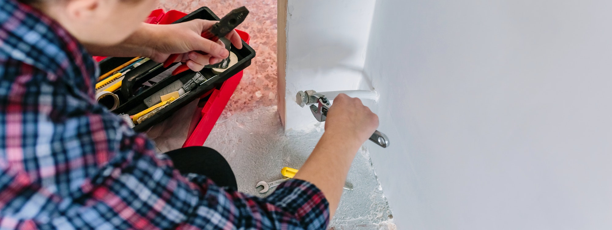 Female plumber tightening pipe with wrench in heating installation